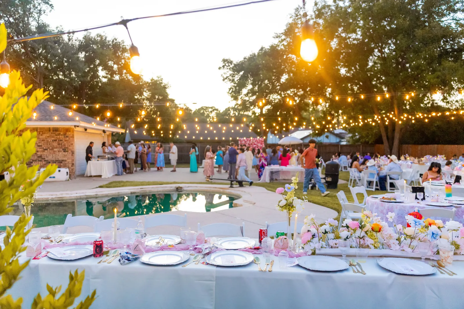 A backyard celebration under string lights by the pool