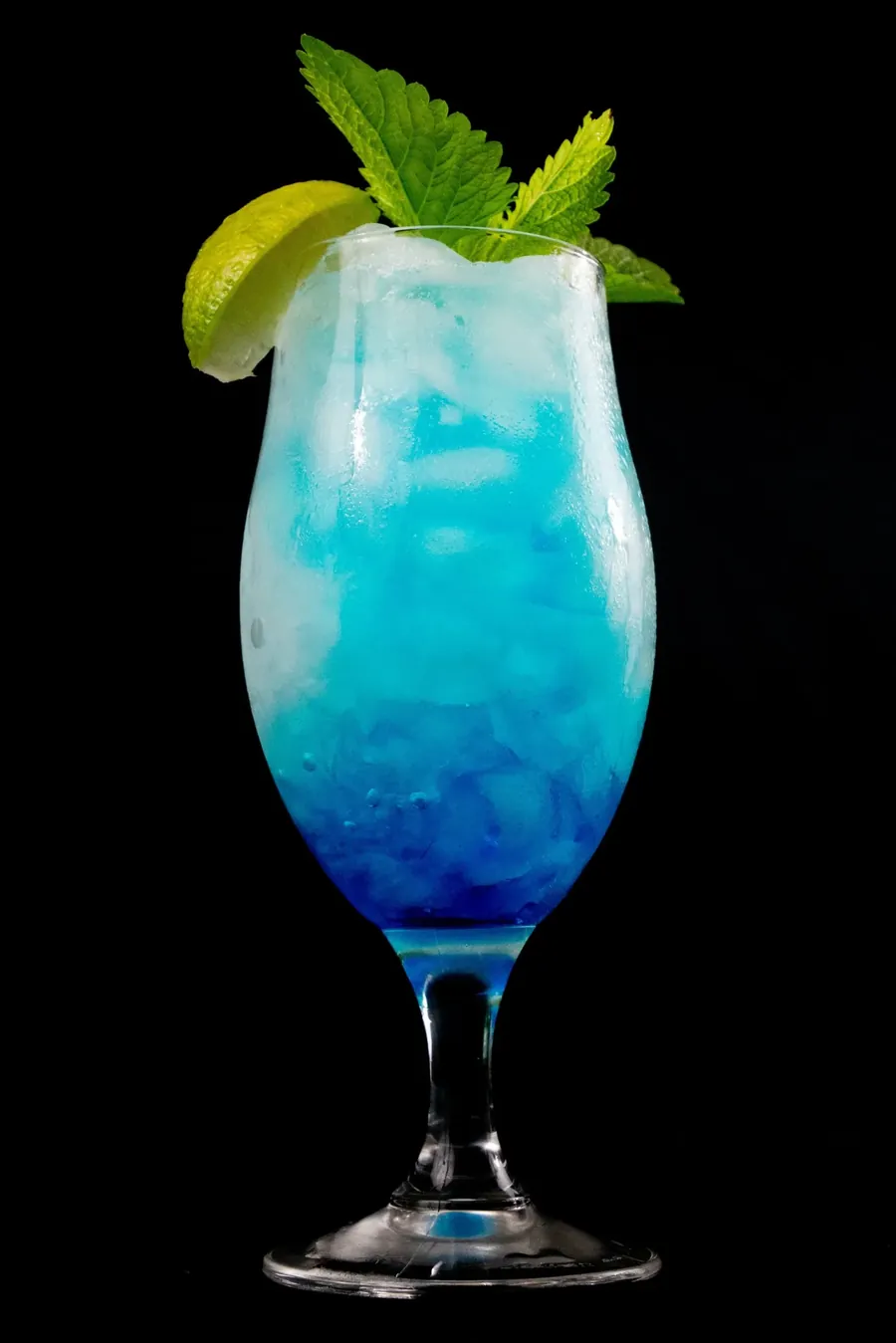 A blue layered cocktail with lime and mint