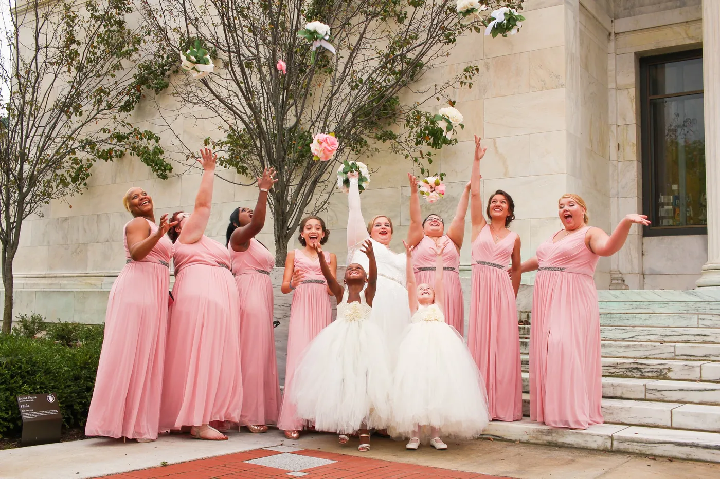 A bridal party tossing bouquets on the steps