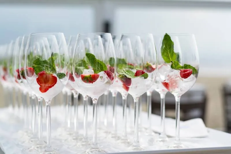 Rows of wine glasses with strawberries and fresh mint